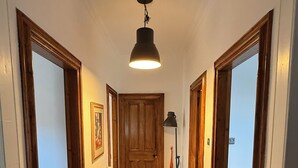 A hallway with wooden doors, a radiator, a hanging light fixture, and a framed picture on the wall. - SPACIOUS 3 BEDROOM VICTORIAN FLAT IN DUNFERMLINE. VERY NEAR TOWN CENTRE ! (Dunfermline)