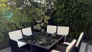 An outdoor patio with a glass-top table surrounded by wicker furniture with white cushions. - SPACIOUS 3 BEDROOM VICTORIAN FLAT IN DUNFERMLINE. VERY NEAR TOWN CENTRE ! (Dunfermline)