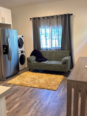 A compact living space with a kitchenette, a sofa, a dining table, and a washing machine. - Cozy 1-bedroom house in pleasant San Marcos with AC (San Marcos)