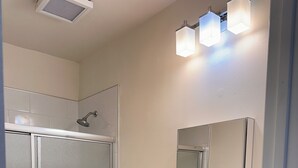 Un bagno con doccia, wc, lavandino e specchio.