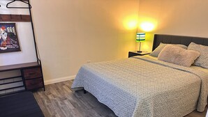 Una camera da letto con un letto, un comodino, una lampada e un'opera d'arte appesa al muro.