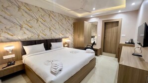A modern hotel room with a large bed, bedside lamps, a flat-screen TV, and a wooden wardrobe.