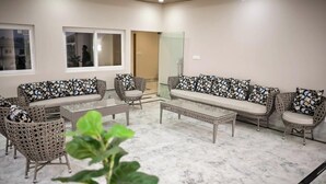 A room with a sofa set, two wicker chairs, a coffee table, and a glass door leading to another room.