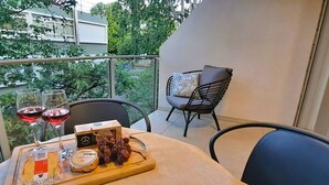 A balcony with a table set for a meal, including cheese, grapes, and wine glasses. - Smart Stay: Modern Apt w/ Free Parking, Near Uni (Dunedin)