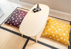 A tatami mat room with a low table and two pillows with floral patterns. - Ustay nippori (Tokyo)