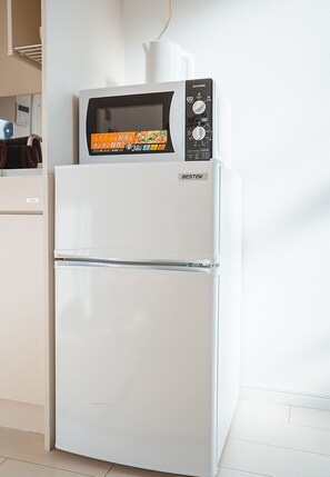 Un refrigerador blanco con un microondas encima, un panel de control y un dispensador de agua.