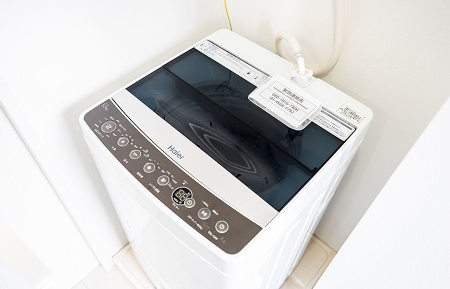 A white appliance with a digital display and control panel, likely a washer or dryer, in a room with white walls and a tiled floor.