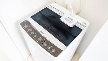 A white appliance with a digital display and control panel, likely a washer or dryer, in a room with white walls and a tiled floor.