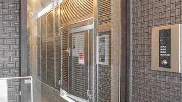 A hotel room entrance with a glass door, a keypad lock, and a patterned wall.