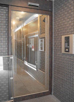 Entrada a una habitación de hotel con puerta de vidrio, cerradura electrónica y pared con diseño.