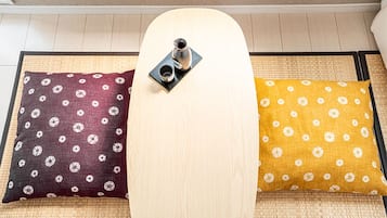 A tatami mat room with a low table and two pillows with floral patterns.