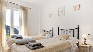 Une chambre avec deux lits, une table de chevet et une vue sur l’extérieur.
