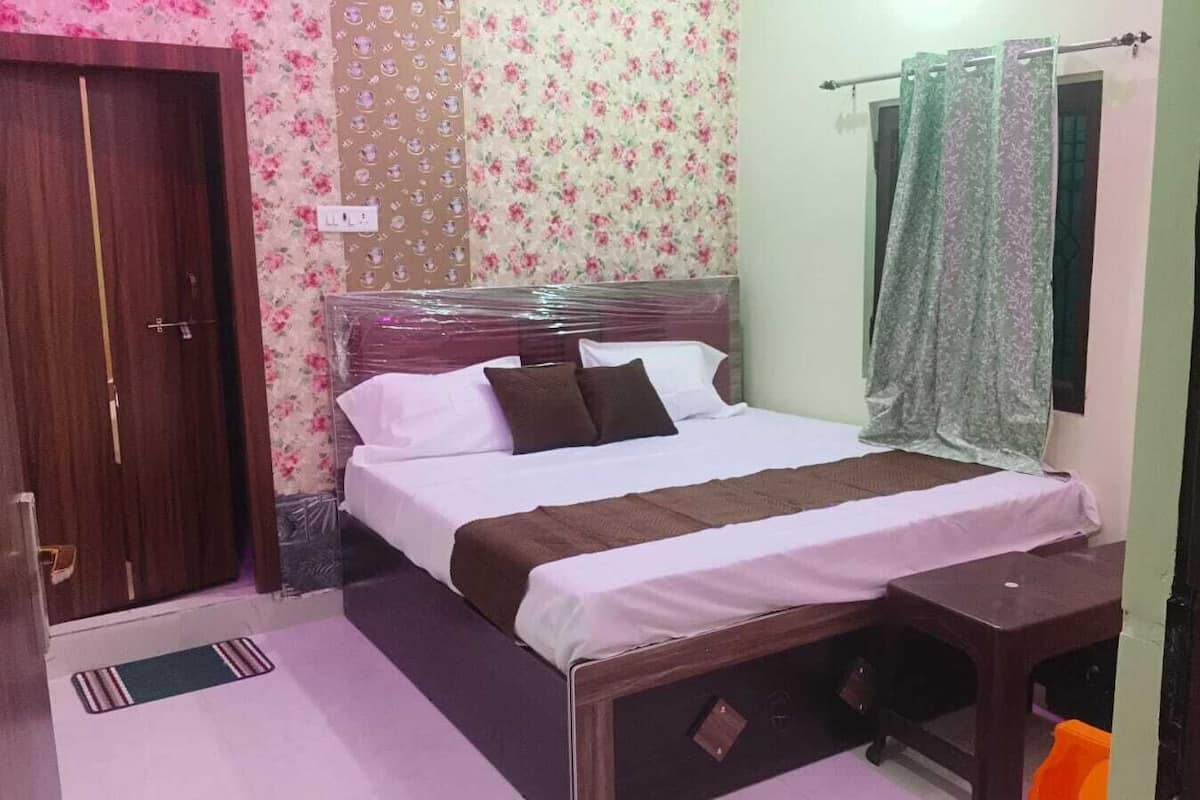 A bedroom with a bed, a wooden wardrobe, a bedside table, and a window with curtains.