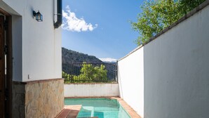 Una piscina petita amb una paret de pedra i un edifici blanc.