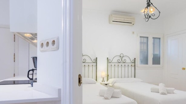 Ett hotellrum med två sängar, ett handfat, en luftkonditioneringsanläggning och en kristallkrona.