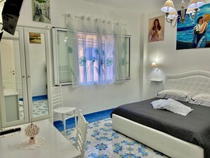 A bedroom with a bed, a chair, a desk, a lamp, and a painting on the wall. - Il Borgo (Vietri sul Mare)