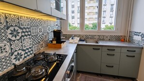 A compact kitchen with a gas stove, a sink, and a window overlooking a residential area. - Luxury Yara apartment with an elevator on the first floor, near the train station (Montargis)