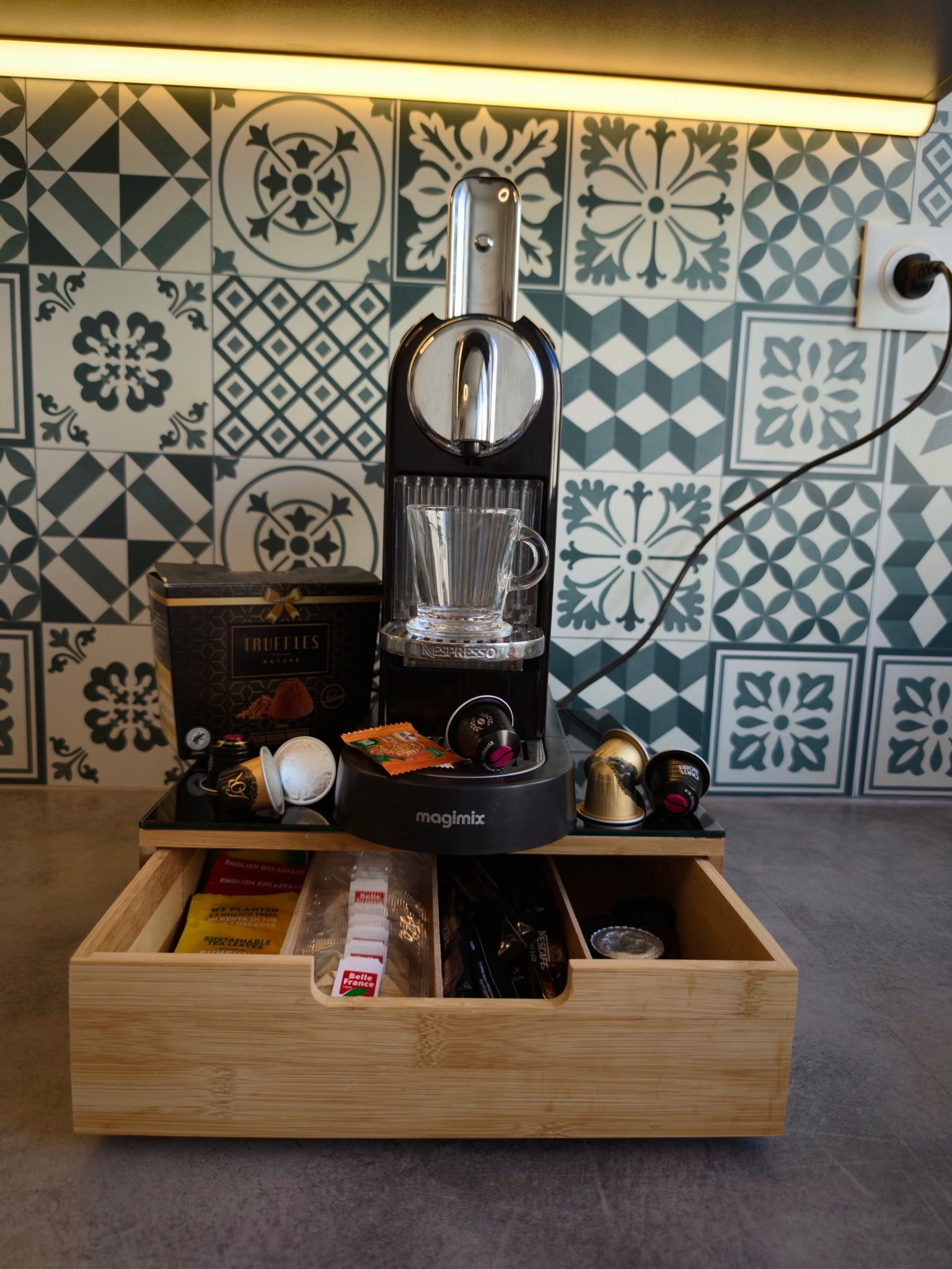 A coffee machine with a glass carafe, a box labeled 'TRUFFLES,' and a wooden drawer with various items.