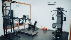 Un gimnasio con equipo de ejercicio, un espejo y una cinta de correr.