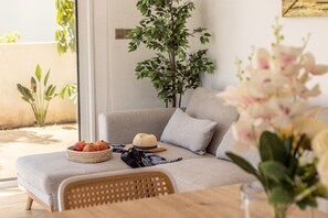 Ein modernes Wohnzimmer mit einer Couch, einem Esstisch, einer Pflanze und einem an der Wand befestigten Kunstwerk.