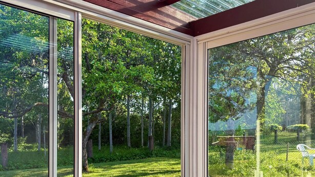 A conservatory with large glass doors, a wooden ceiling, and a view of a lush garden. - 4 Star Holiday Home in Sodra vi (Sodra Vi)