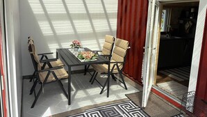 A dining area with a table and chairs, a view of the outside, and a door leading to a kitchen. - 4 Star Holiday Home in Sodra vi (Sodra Vi)