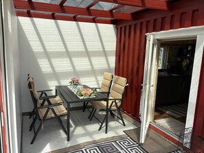A dining area with a table and chairs, a view of the outside, and a door leading to a kitchen. - 4 Star Holiday Home in Sodra vi (Sodra Vi)