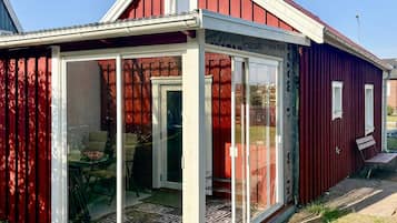 Un bâtiment rouge avec une entrée dotée d’une porte en verre, un petit porche et une vue dégagée sur l’intérieur.