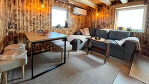 A cozy room with wooden walls, a sofa, a table, and a window. - 4 Star Holiday Home in Sodra vi (Sodra Vi)
