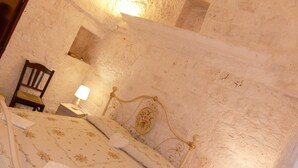 Quarto com cama, cadeira, mesa de cabeceira e abajur.