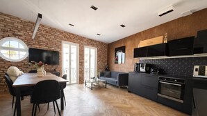 Eine moderne Küche mit schwarzem Arbeitsplatz, einem eingebauten Backofen und einem Essbereich mit Holztisch und -stühlen.
