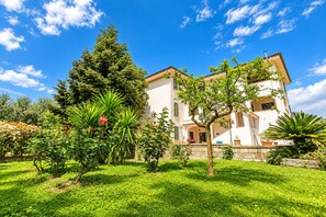 A two-story building with a garden in front, surrounded by trees and shrubs. - De Vivo Realty - Villa Teresa (Piano di Sorrento)