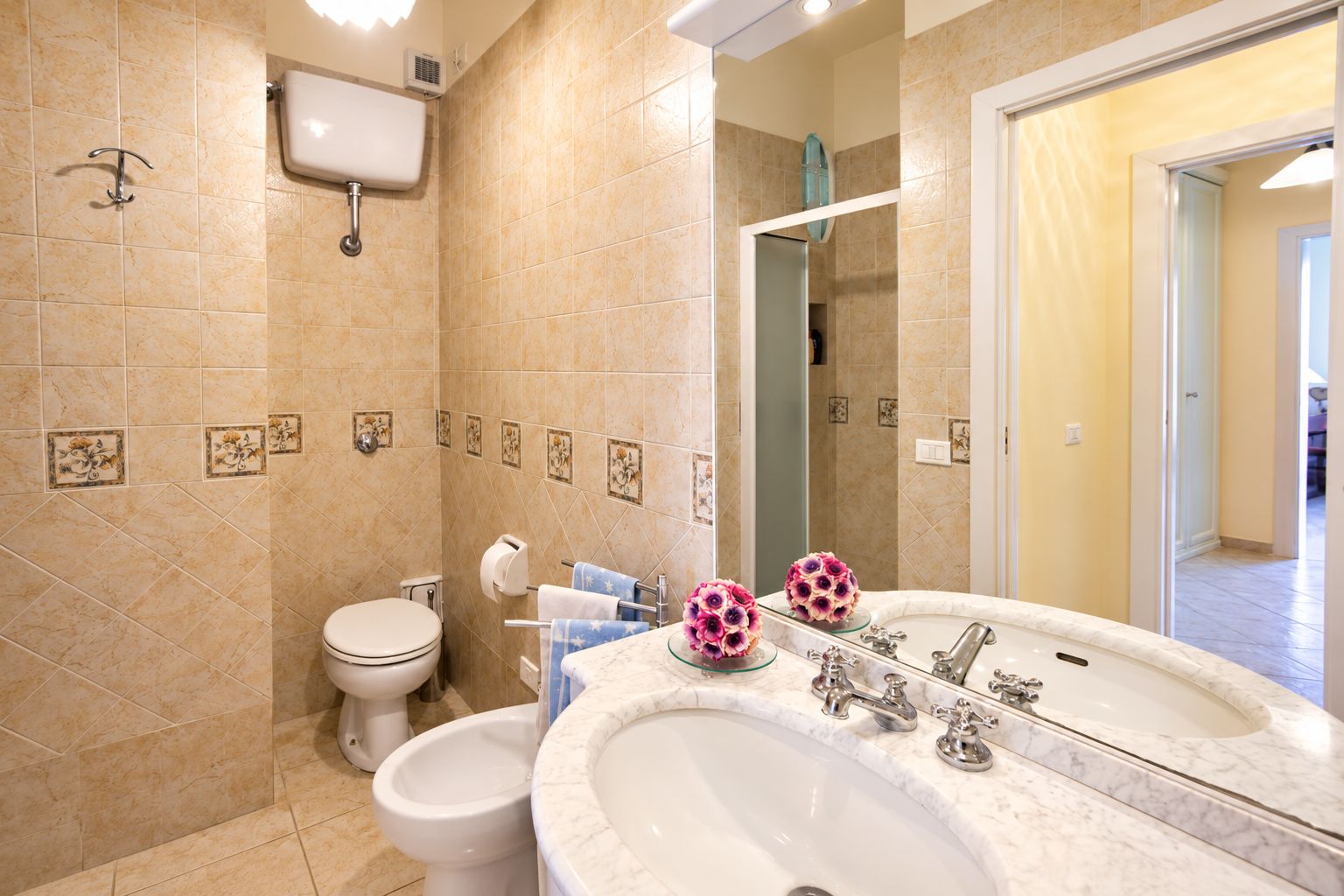 A bathroom with a toilet, bidet, sink, and a mirror.