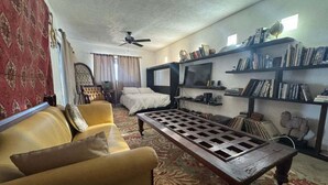 Uma sala de estar com sofá, mesa de centro, televis ão e estantes.