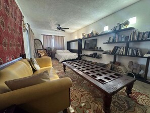 A living room with a sofa, a coffee table, a television, and bookshelves. - Mision Los Sahuaros #72 - 2BR with Rooftop Deck (San Felipe)
