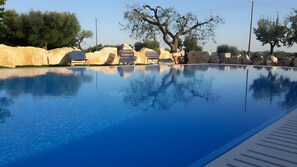 A clear swimming pool with lounge chairs and a rocky landscape in the background. - Apartment 'Trullo Country Relax Lumieri 4' with Shared Pool, Wi-Fi and Air Conditioning (Martina Franca)