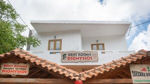 A building with a sign for 'RENT ROOMS DIONYSSSOS' and 'TAVERNARIA DIONYSSSOS'.