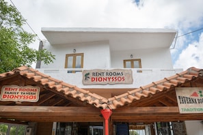 Un edificio con un letrero que dice 'RENT ROOMS DIONYSSSOS' y 'TAVERNARIA DIONYSSSOS'.