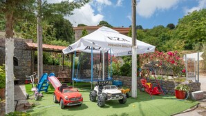 A children's play area with a trampoline, slides, and toy cars.