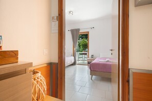 A bedroom with a bed, a bedside table, a window with curtains, and a view of the outdoors. - Room 'Hestia' with Wi-Fi (Lasithiou)