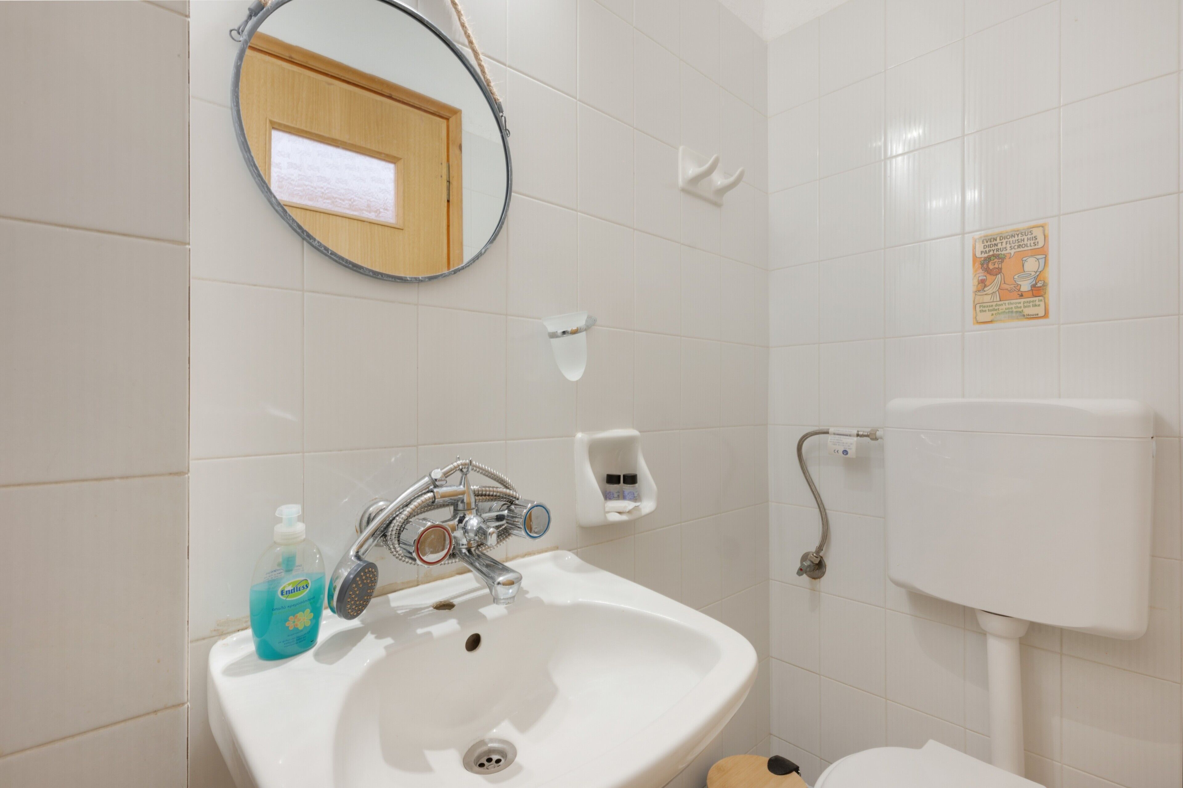 Un baño con lavabo, espejo, inodoro y dispensador de jabón.