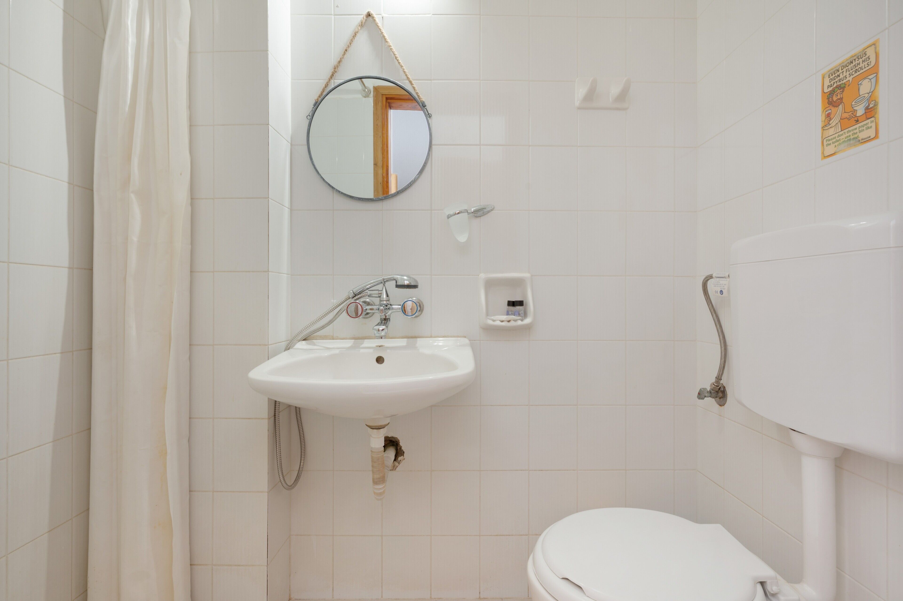A bathroom with a sink, mirror, toilet, and shower curtain.