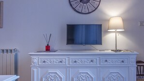 A room with a white ornate dresser, a flat-screen TV, a wall clock, and a lamp. - Siqillya Etna Linguaglossa (Linguaglossa)