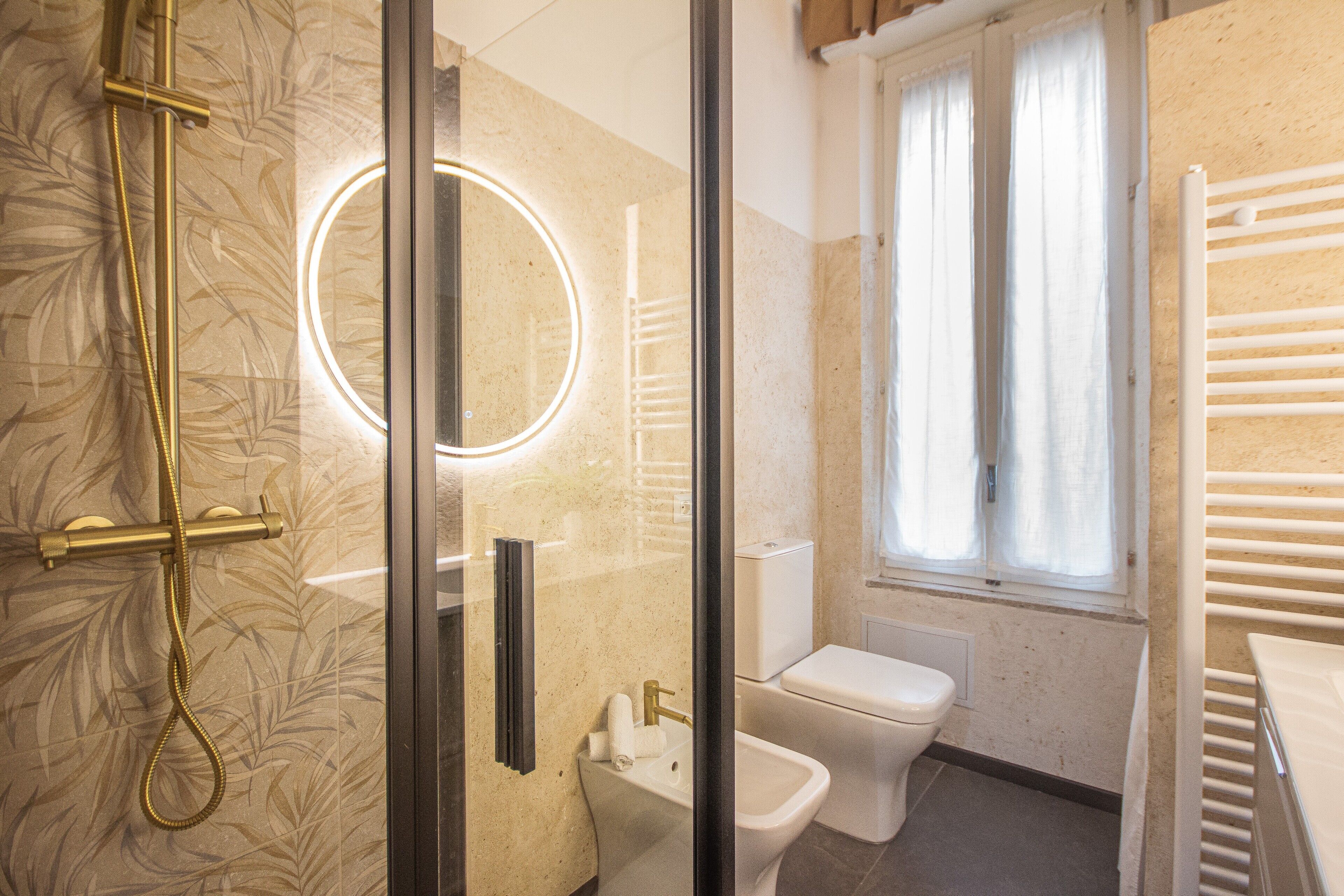 Een badkamer met een douchecabine van glas, een toilet en een bidet.