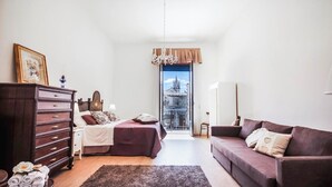 A bedroom with a bed, dresser, and a sofa. There is a view of a building through a door. - Siqillya Etna Linguaglossa (Linguaglossa)