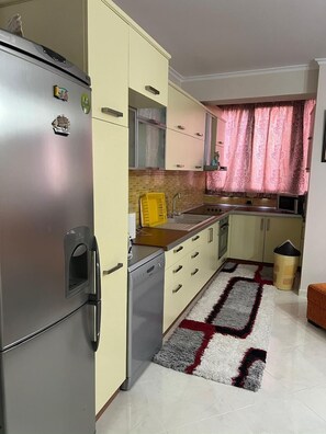 Eine kleine Küche mit Kühlschrank, Geschirrspüler und Spüle.