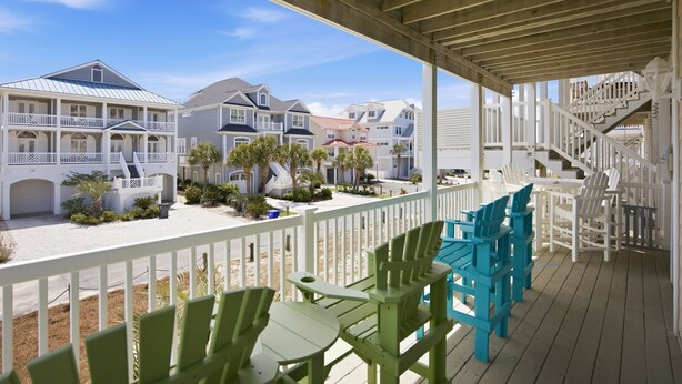 A covered outdoor area with wooden deck, white railings, and green chairs. - unobstructed ocean views-pool club-private bath for each bedroom-elevator-parking 4 cars-golf cart friendly<br>APRIL '26 UPDATES- new floors, paint, HVAC, renovated walk in shower (Ocean Isle Beach)