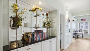 A kitchen with white cabinetry, a black countertop, and a glass shelving unit displaying books and decorative items. - unobstructed ocean views-pool club-private bath for each bedroom-elevator-parking 4 cars-golf cart friendly<br>APRIL '26 UPDATES- new floors, paint, HVAC, renovated walk in shower (Ocean Isle Beach)