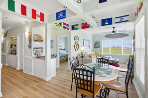 Un coin repas avec une table ronde et des chaises, un ventilateur de plafond et divers drapeaux suspendus au plafond.
