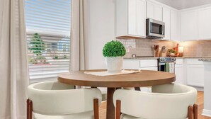 A modern kitchen with white cabinets, a microwave, and a round table with two chairs. - Spring Haus Near Downtown (New Braunfels)